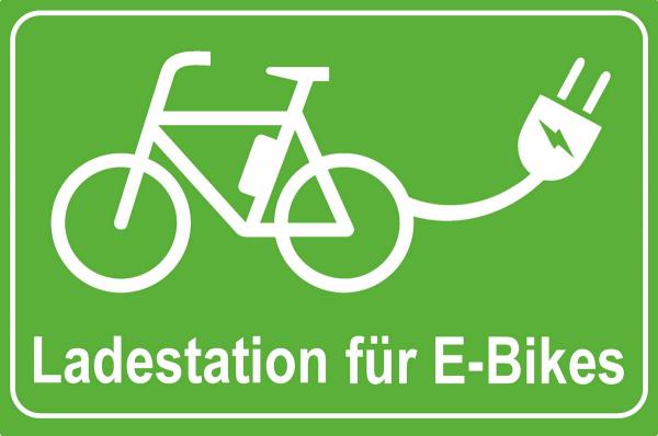 Grünes Hinweisschild mit weißer Schrift E-Bike Ladestation sowie e-Bike Symbol